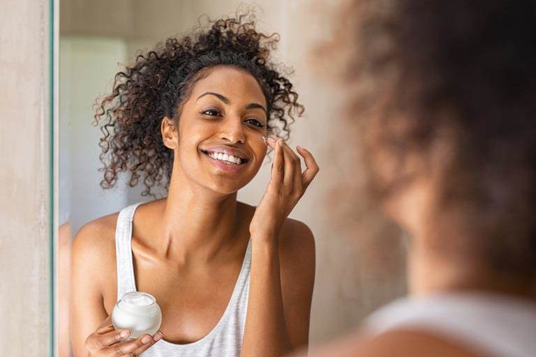 lady applying face cream in the mirror